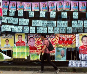 SEA OF POSTERS  A man walks past campaign posters of candidates in Monday’s barangay elections hanging at a waiting shed at P. Bernardo Elementary School in Quezon City. Environmentalist groups are urging the candidates to clean up their mess no matter what the outcome of the polls is.  ARNOLD ALMACEN