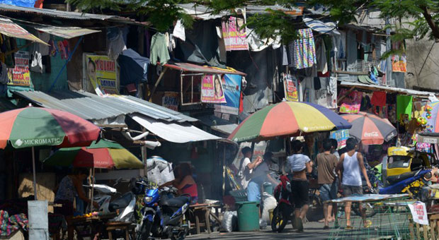 Pedetrians walk past houses in a shantytown in Manila on July 5, 2013. AFP