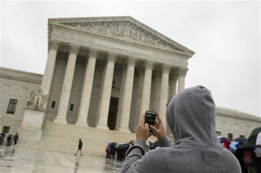 This April 29, 2014 file photo shows a Supreme Court visitor using his cellphone to take a photo of the court in Washington. AP