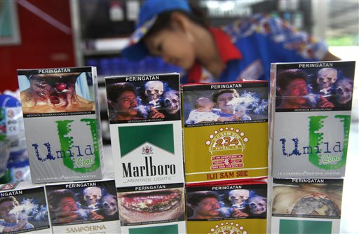 New packs of cigarettes displaying pictorial health warnings are arranged on the counter by a shop attendant for photographers at a convenience store in Jakarta, Indonesia, Tuesday, June 24, 2014. Tobacco companies on Tuesday largely snubbed an Indonesian law requiring them to put graphic photo warnings on all cigarette packs being sold, marking another setback in a country that's home to the world's highest rate of men smokers and a wild, wild west of advertising.  AP