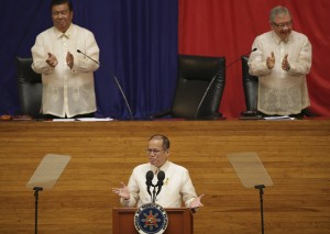 Philippine President Benigno Aquino III, center, gestures as he is applauded by Senate President Franklin Drilon, left, and House Speaker Feliciano Belmonte Jr. during the start of his 5th State of the Nation Address during the joint session of the 16th Congress at the House of Representatives in suburban Quezon city, north of Manila, Philippines Monday July 28, 2014. (AP Photo/Aaron Favila)