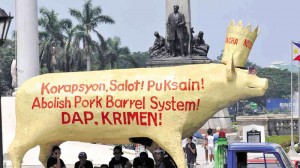 GOLDEN PIG AS NEW IDOL  Members of organizations taking part in the “Stand Up, Sign Up” people’s initiative against all forms of pork barrel at Rizal Park in Manila take cover from the heat under a giant papier-mâché golden pig.  RICHARD A. REYES