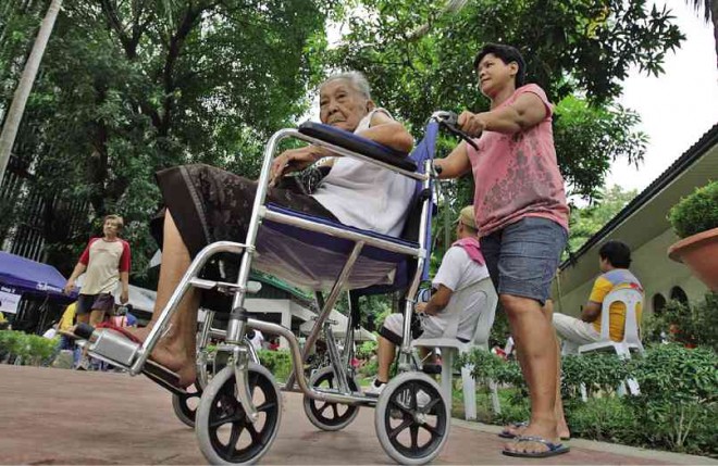 An elderly woman on a wheelchair being pushed. For story: DSWD backs removal of senior citizen’s purchase booklet
