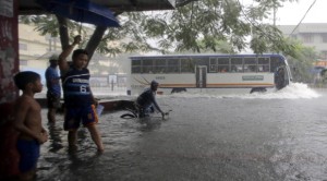 Commuters cross a flooded street for a fee after heavy monsoon rains spawned by tropical storm Fung-Wong (local name Mario) flooded Manila and most parts of the metropolis Friday, Sept 19, 2014 in the Philippines. AP
