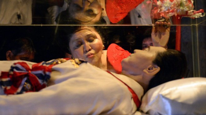 Former Philippine first lady and now congresswoman, Imelda Marcos, kisses the glass case of her late husband president Ferdinand Marcos during a visit to the mausoleum on her 85th birthday in Batac town, Ilocos norte, north of Manila on July 2, 2014. President Aquino has not changed his mind about disallowing the burial of the late President Ferdinand Marcos among heroes at Libingan ng mga Bayani, Malacañang said on Sunday, the 42nd anniversary of Marcos’ declaration of martial law.  AFP PHOTO/TED ALJIBE