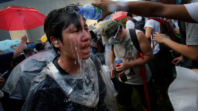 A student protester is overcome by pepper spray from riot police as thousands of protesters surround the government headquarters in Hong Kong Sunday, Sept. 28, 2014. Hong Kong police blasted pro-democracy protesters with tear gas and used vans with flashing lights in renewed efforts overnight to force demonstrators from streets near the government headquarters, as the city's top leader early Monday urged them to go home.  AP PHOTO/WALLY SANTANA