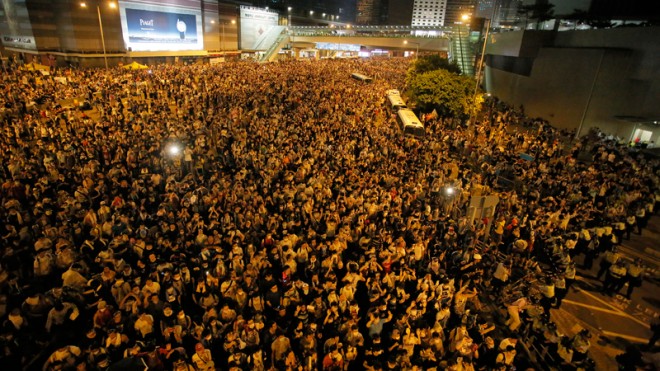 Protesters gather at a main road in the financial central district after riot police use tear gas against them after thousands of people blocked the road in Hong Kong, Sunday, Sept. 28, 2014. Hong Kong police used tear gas on Sunday and warned of further measures as they tried to clear thousands of pro-democracy protesters gathered outside government headquarters in a challenge to Beijing over its decision to restrict democratic reforms for the city.  AP PHOTO/VINCENT YU  