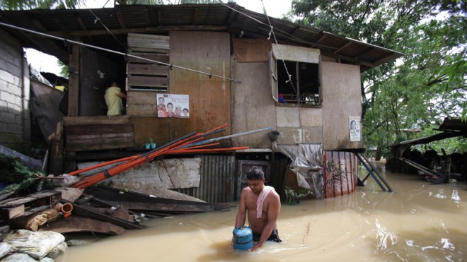 A Filipino wades through floodwaters as residents who earlier evacuated due to a swollen river return to their homes in suburban Quezon city, Philippines Monday, Sept. 15, 2014. Fast-moving typhoon Kalmaegi blew out of the northern Philippines Monday after causing flash floods and landslides. Three people died when big waves and strong winds sank a stalled ferry over the weekend. (AP Photo/Aaron Favila)