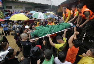 Rescuers unload the body of a man who died of natural causes at the height of heavy flooding brought about by tropical storm Fung-Wong flooded Marikina city, east of Manila, Philippines and most parts of the metropolis Friday, Sept. 19, 2014.  AP