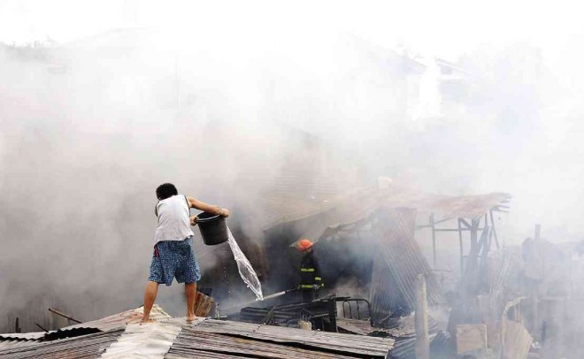 A RESIDENT tries to help put out the fire in his community in the village of Camputhaw, Cebu City, on Sept. 17. CHRISTIAN MANINGO/CEBU DAILY NEWS 