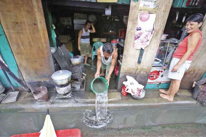 AN EATERY owner tries to remove floodwater from his place following heavy rain in Cebu City last week.  JUNJIE MENDOZA/CEBU DAILY NEWS 