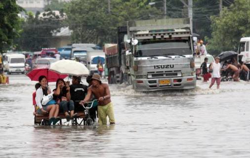 A pedicab driver transports people to the other end of the flooded road. CDN/JUNJIE MENDOZA