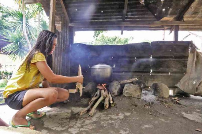 A WOMAN cooks her family’s meal at a shelter for residents of areas within a six-kilometer radius danger zone around Mayon Volcano. MARC ALVIC ESPLANA/INQUIRER SOUTHERN LUZON