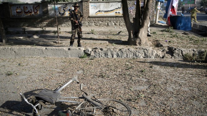 An Afghan security guard stands at the site of a suicide attack in Kabul, Afghanistan, Wednesday, Oct. 1, 2014. Two suicide bombers in the Afghan capital targeted two buses carrying Afghan army troops on Wednesday, killing several people and wounding over a dozen others, police said. (AP Photo/Massoud Hossaini)