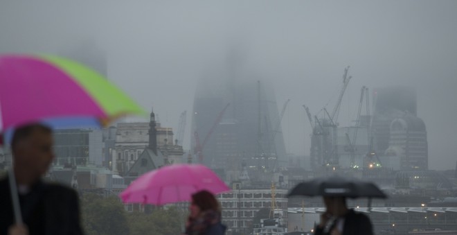 Low cloud envelops office blocks in the City of London as pedestrians walk across Waterloo Bridge over the River Thames in London on Oct. 13, 2014. Around one in 10 flights may be canceled at Britain's biggest airport Heathrow on Tuesday, Oct. 21, due to stormy weather, an airport spokesman said.  AP PHOTO/ALASTAIR GRANT 