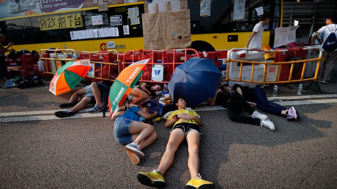 Student activists sleep in the shade of umbrellas, on a road near the government headquarters where pro-democracy activists have gathered and made camp, Tuesday, Sept. 30, 2014, in Hong Kong. Ubiquitous images in Hong Kong media with masses of unarmed students fending off pepper spray with umbrellas could not contrast more starkly with mainland China’s virtual blackout of news about the territory’s pro-democracy protests. (AP Photo/Wong Maye-E)