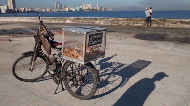 The shadow of self-employed Juan Carlos Lazo is cast on the cement next to his motorized bicycle which he uses to sell donuts along the Malecon in Havana, Cuba, early Tuesday, Oct. 28, 2014. The U.N. General Assembly is expected to vote on Tuesday to condemn the U.S. commercial, economic and financial embargoagainst Cuba for the 23rd year in a row. The embargo was first enacted in 1960 following Cuba'snationalization of properties belonging to U.S. citizens and corporations. Sanctions against the Caribbean nation were further strengthened to a near-total embargo in 1962. (AP Photo/Franklin Reyes)