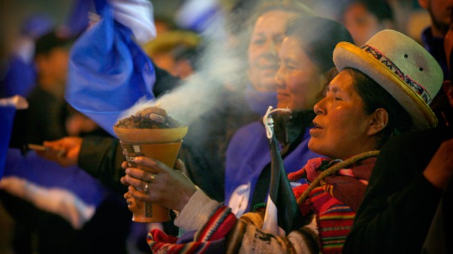 An Aymara indigenous woman burns incense in celebration as supporters wait for President Evo Moralesoutside the presidential palace in La Paz, Bolivia, Sunday Oct. 12, 2014. Evo Morales easily won an unprecedented third term as Bolivia's president Sunday according to an unofficial quick count of the vote.(AP Photo/Enric Marti)