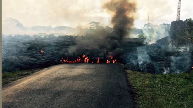 In this Oct. 24, 2014 photo from the U.S. Geological Survey, the lava flow from Kilauea Volcano that began June 27 is seen as it crossed Apa?a Street near Cemetery Road near the town of Pahoa on the Big Island of Hawaii. Hawaii authorities on Saturday told several dozen residents near the active lava flow to prepare for a possible evacuation in the next three to five days as molten rock oozed across the country road and edged closer to homes. The USGS says the flow is currently about 160 to 230 feet (50 to 70 meters) wide and moving northeast at about 10 yards (nine meters) per hour. It's currently about six-tenths of a mile (one kilometer) from Pahoa Village Road, the town's main street. (AP Photo/U.S. Geological Survey)