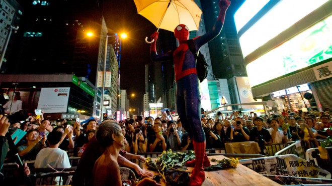 A pro-democracy protester dressed as Spider-man, holding a yellow umbrella, stands on a barricade in the occupied area in the Mong Kok district of Hong Kong, Friday, Oct. 24, 2014. Pro-democracy protesters in Hong Kong plan to hold a spot referendum Sunday on whether to stay in the streets or accept government offers for more talks and clear their protest camps. (AP Photo/Kin Cheung)