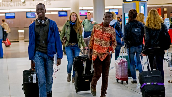 Thomas Nellon, left, 17, and his brother Johnson Nellon, 14, of Liberia, smile at their mother in the arrivals area at John F. Kennedy International Airport in New York, Saturday, Oct. 11, 2014, upon seeing her after passing through customs. The brothers received a health screening upon arrival from a flight they connected with in Europe, the first day of Ebola screening at the JFK. (AP Photo/Craig Ruttle)