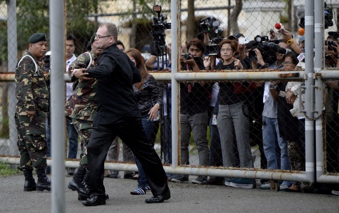 German Marc Susselbeck (in black), boyfriend of murdered Filipino transgender woman Jennifer Laude, also known as “Jeffrey,” confronts soldiers after climbing the gate of the facility where Private First Class Joseph Scott Pemberton is detained at the Armed Forces of the Philippine (AFP) headquarters in Manila on October 22, 2014. AFP PHOTO / NOEL CELIS 
