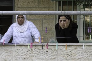 In this photo taken Tuesday, Sept. 30, 2014, two Palestinian women stand at their balcony over looking the entrance of the neighboring house that belongs to Palestinian Ziad Qarain, which Jewish settlers moved into, at the Palestinian neighborhood of Silwan, East Jerusalem. AP