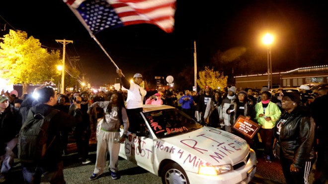 Protesters arrive at the Ferguson Police Department Saturday, Oct. 11, 2014, for a rally in remembrance of Michael Brown in Ferguson, Mo. On Aug. 9, 2014, a white police officer fatally shot the unarmed Brown, in theSt. Louis suburb. (AP Photo/Charles Rex Arbogast)