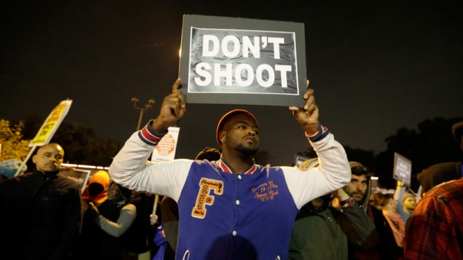 Protesters gather across the street from the Ferguson, Mo., police station in a continuing protest of the shooting of Michael Brown, Friday, Oct. 10, 2014, in Ferguson, Mo. (AP Photo/Charles Rex Arbogast)
