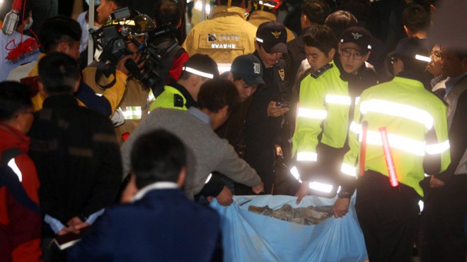 Police officers carry a sack containing shoes of victims after a ventilation grate was collapsed at an outdoor theater in Seongnam, south of Seoul, South Korea, Friday, Oct. 17, 2014. Fourteen people were feared dead Friday after the ventilation grate collapsed during a concert by popular girls’ band 4Minute, officials said. (AP Photo/Yonhap, Shin Young-geun) 