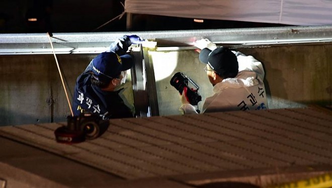 South Korean National Forensic Service members check a broken ventilation grate after concert goers fell through it into an underground parking area below in Seongnam City, south of Seoul, on Oct 17, 2014. PHOTO/AFP 