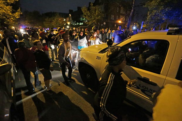 A crowd gathers Wednesday near the scene in south St. Louis where a man was fatally shot by an off-duty St. Louis police officer on Wednesday, Oct. 8, 2014. St. Louis Police Lt. Col. Alfred Adkins said the 32-year-old officer was working a secondary security job late Wednesday when the shooting happened. AP