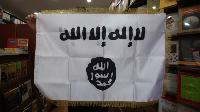 In this Monday, Oct. 13, 2014 photo, a man shows an IS flag at an Islamic bookstore in the Fatih district ofIstanbul. A Sept. 26 clash, described to The Associated Press by Korkut and a half a dozen other university students, was the first in a series of fights at Istanbul University’s Beyazit campus. There has been repeated violence since, and Turkish media have reported scores of arrests. (AP Photo/Emrah Gurel)