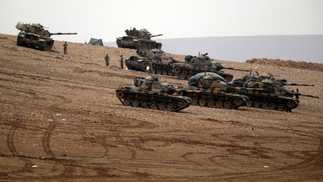 Turkish soldiers hold their positions with their tanks on a hilltop on the outskirts of Suruc, at the Turkey-Syria border, overlooking Kobani, Syria, during fighting between Syrian Kurds and the militants of Islamic State group, Sunday, Oct. 12, 2014. Kobani, also known as Ayn Arab, and its surrounding areas, has been under assault by extremists of the Islamic State group since mid-September and is being defended by Kurdish fighters.(AP Photo/Lefteris Pitarakis)