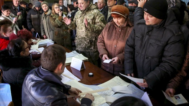 Ukrainian President Petro Poroshenko, center, speaks with local staff at a poling station during voting in parliamentary elections in Kramatorsk, Donetsk region, Ukraine, Sunday, Oct. 26, 2014. Voters in Ukraineheaded to the polls Sunday to elect a new parliament, overhauling a legislature tainted by its association with ousted President Viktor Yanukovych. (AP Photo/Mikhail Palinchak, Pool)