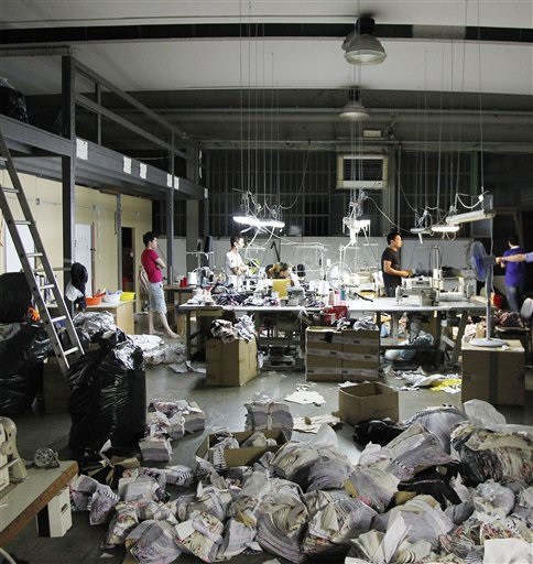 In this June 19, 2014 photo, Chinese workers stand in a sequestered textile factory in Prato, Italy. The compound, which had been divided into four different factories, was closed because of illegal bedrooms, too few fire extinguishers, no well-marked, easily accessible fire exits, no first aid kit and a dozen gas canisters found during the raid. Of the 44 workers at the factory, 35 were without proper contracts or social security contributions, and six did not have the legal right to stay in Italy. AP
