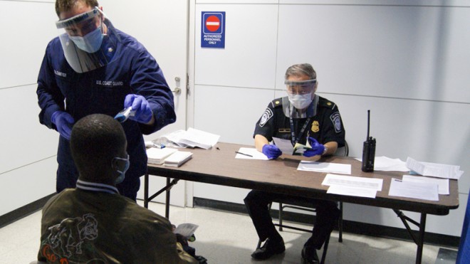 In this Thursday, Oct. 16, 2014, file photo released by U.S. Customs and Border Protection, U.S. Coast Guard Health Technician Nathan Wallenmeyer, left, and CBP supervisor Sam Ko, right, conduct prescreening measures on a passenger who has arrived from Sierra Leone at O'Hare International Airport's Terminal 5 in Chicago. Demands are rising in Washington for the U.S. to ban travelers from countries in West Africa, but the Obama administration is resisting and says the screening measures already in place for travelers are more effective. (AP Photo/U.S. Customs and Border Protection, Melissa Maraj, File)