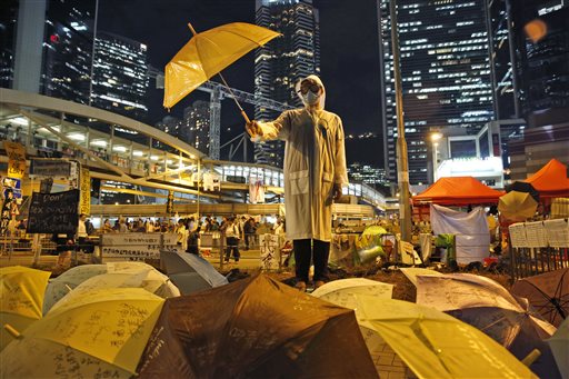 In this Thursday, Oct. 9, 2014 photo, a protester holds an umbrella during a performance on a main road in the occupied areas outside government headquarters in Hong Kong's Admiralty in Hong Kong.  AP