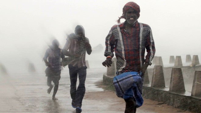 People run for shelter as heavy rain and wind gusts rip through the Bay of Bengal coast at Gopalpur, Orissa, about 285 kilometers (178 miles) north east of Visakhapatnam, India, Sunday, Oct. 12, 2014. A powerful cyclone was pounding a large swath of India's eastern seaboard with heavy rain and strong winds on Sunday, killing at least two people and causing major damage to buildings and crops, in one of two storms lashing Asia. (AP Photo/Biswaranjan Rout)