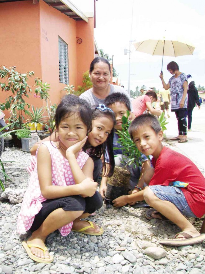 RESIDENTS of new houses in the San Roque resettlement project in New Bataan, Compostela Valley province, pose for a picture after planting calamansi outside their new house. The resettlement project is for survivors of Typhoon “Pablo.” Photo:FRINSTON L. LIM