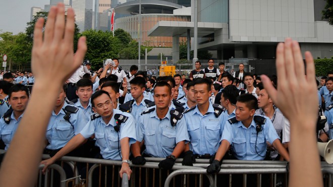 A student protester raises his hands as a gesture of their nonviolent intentions as they resist during change of shift for local police but backed down after being reassured they could reoccupy the pavement outside the government compound’s gate, Thursday, Oct. 2, 2014 in Hong Kong. Hong Kong police warned of serious consequences if pro-democracy protesters try to occupy government buildings, as they have threatened to do if the territory's leader doesn't resign by Thursday. (AP Photo/Wong Maye-E)