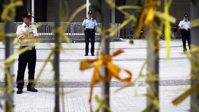 Police officers stand guard at the legislative council compound behind a fence decorated with yellow ribbons, which have become a symbol for people to show their solidarity with protesters occupying parts of Hong Kong to demand genuine democratic reform, Saturday, Oct. 4, 2014 in Hong Kong. But as part of a backlash against the protesters, a new opposition “blue ribbon” group has emerged.  AP PHOTO/WONG MAYE-E 