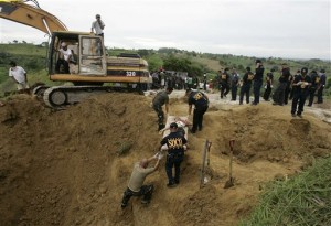  In this Nov. 24, 2009 file photo, police officers carry one of dead bodies they recovered along a hillside in Datu Ampatuan, Maguindanao province, southern Philippines. Five years after gunmen flagged down a convoy of cars and massacred all 58 occupants, including scores of journalists, in a southern Philippine province, the body count continues to rise.(AP Photo/Aaron Favila, File)