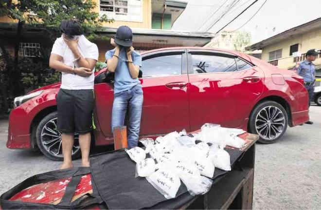 LOAD OF TROUBLE Suspected drug pushers Alimar Sulaiman (left) and his teenage cohort are found carrying several packs of “shabu” worth P4 million in their car in a buy-bust operation of the Quezon City Police District on Wednesday. LYN RILLON