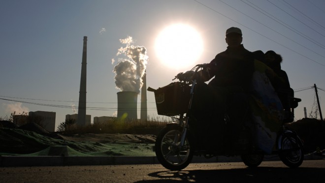A family riding an electric tricycle bike is silhouetted against the sun setting on a coal-fired power plant in Beijing, China Thursday, Nov. 13, 2014. Chinese leaders pledged for the first time to cap the country’s decades-long growth of greenhouse gas emissions. Since China emits more carbon and other heat-trapping gases than any other country, the pledge boosted global efforts to prevent catastrophic climate change. Fulfilling its pledge, however, will require China to transform a booming economy that still largely depends on polluting industries such as steel production and manufacturing. (AP Photo/Andy Wong)
