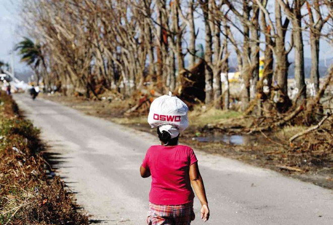 A woman carries relief items for her family in San Jose District, Tacloban City. This photo was  taken on Nov. 26, 2013. RAFFY LERMA
