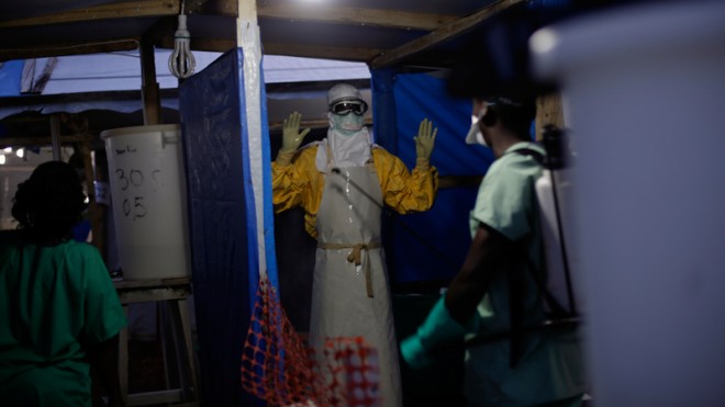 In this picture taken Thursday Nov. 20, 2014, an MSF Ebola heath worker is sprayed as he leaves the contaminated zone at the Ebola treatment centre in Gueckedou, Guinea. Officials in Guinea say bandits during a roadside robbery stole a cooler containing blood samples that are believed to have Ebola, from a vehicle traveling from Kankan prefecture in central Guinea to a test site in Gueckedou, in the south.(AP Photo/Jerome Delay)