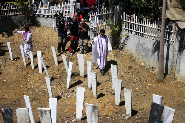 Catholic priests bless markers where 58 people were killed at the massacre site in Ampatuan town, Maguindanao province, in southern island of Mindanao on November 21, 2014, ahead of the fifth anniversary of the worst political massacre of the country.  Five years after 58 people were killed in the Philippines' worst political massacre, anger among victims' relatives is building, with no one yet convicted and the alleged masterminds still enjoying power. AFP PHOTO/Mark Navales