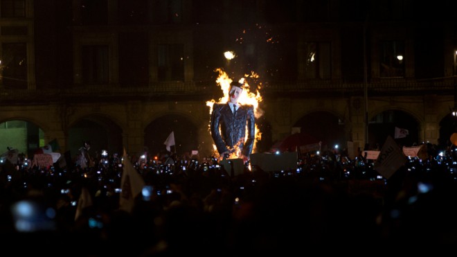 An effigy depicting Mexico's President Enrique Pena Nieto is set on fire during a massive march in Mexico City, Thursday, Nov. 20, 2014. Protesters marched in the capital city to demand authorities find 43 missing college students, seeking to pressure the government. Mexico officially lists more than 20 thousand people as having gone missing since the start of the country's drug war in 2006, and the search for the missing students has turned up other, unrelated mass graves. (AP Photo/Moises Castillo)