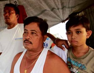 THREE GENERATIONS OF SURVIVORS Pedro Lacandazo, 58, flanked by son Pedro Lacandazo Jr. (left) and 12-year-old grandson John Paul Madrigal, survived but lost 22 members of his family to the typhoon. DANNY PETILLA/CONTRIBUTOR